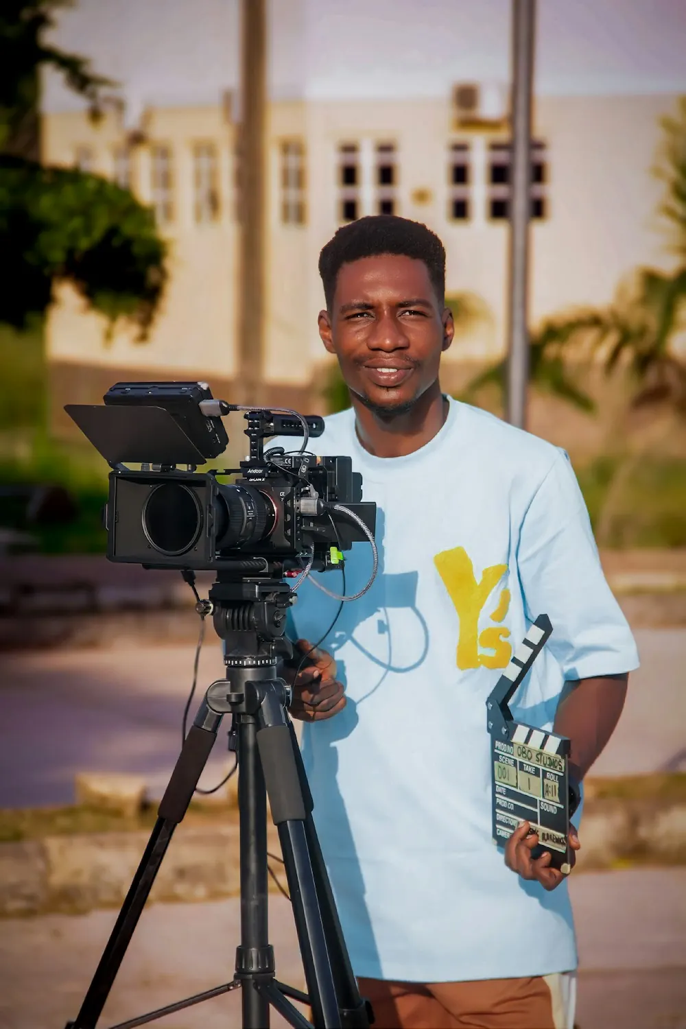 A videographer standing behind a camera on a tripod